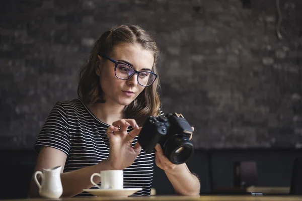 Mujer joven fotografiando chillando sus fotos mientras se sienta relajándose tomando café — Foto de Stock