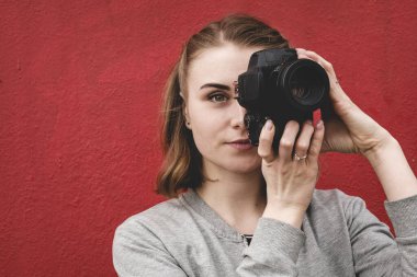 Resimde bir fotoğraf makinesi tutan kadın fotoğrafçı.