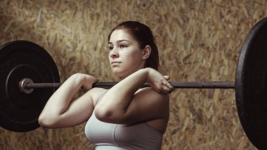 Genç bayan sporcu halterle çalışıyor.