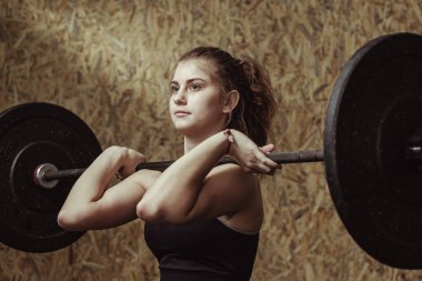 Genç bayan sporcu halterle çalışıyor.