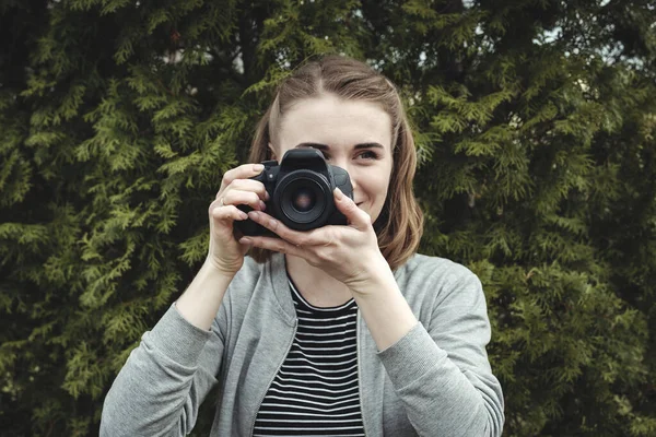 Ung kvinna står utomhus fotografering på en kamera med fokus — Stockfoto