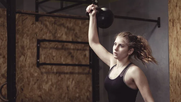 Jovem mulher trabalhando com um peso kettlebell — Fotografia de Stock