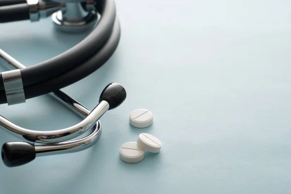 Drie Witte Tabletten Buurt Van Een Stethoscoop Een Witte Achtergrond — Stockfoto