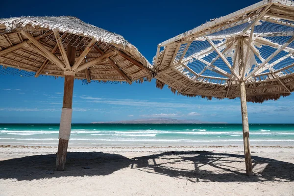 Большие деревянные зонтики на песчаном тропическом пляже — стоковое фото