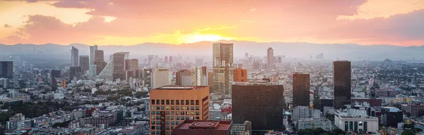 Aerial view from Torre Latinoamericana of Mexico city downtown skyscrappers and mountains at sunset