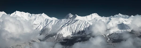 Astonishing panoramic view on Caucasus mountains from the Rosa Peak. Snowy mountains and low dramatic clouds. Sochi; Krasnaya Polyana (Rosa Khutor alpine ski resort); Western Caucasus; Russia.