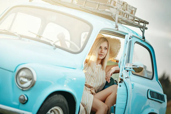 一个年轻的女人坐着一辆蓝色的古董车在夏天旅行 — 图库照片