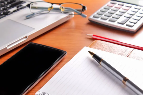 Ofis işyeri dizüstü bilgisayar ve tahta masalarda akıllı telefon