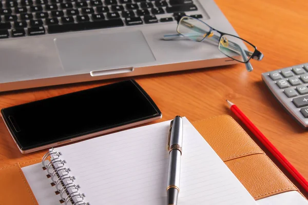 Ofis işyeri dizüstü bilgisayar ve tahta masalarda akıllı telefon