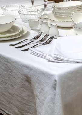 Beyaz tabak, çatal bıçak ve peçete beyaz masada.