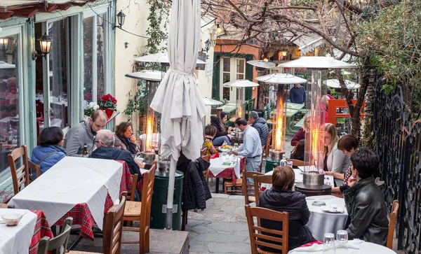 Atina, Yunanistan - 18 Şubat 2020. Atina 'nın geleneksel bir mahallesi olan Plaka' nın dar sokaklarındaki Palio Tetradio restoranındaki turistler, Yunanistan 'ın Akropolis kentinin yamaçlarında yer alıyorlar.