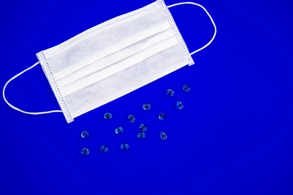 corona virus mask for protecting against the ncov covid-19 virus with fish oil pills on blue background