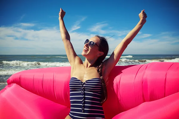 Una mujer francamente sonriente que se estira en un bote de aire rosa profundo — Foto de Stock