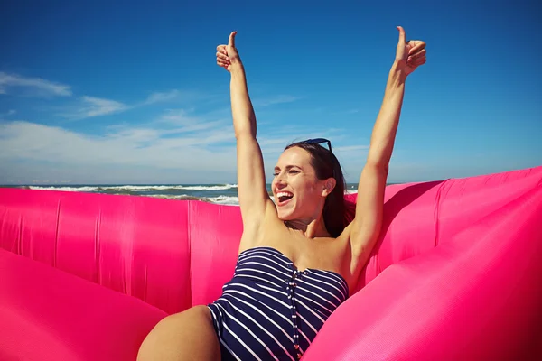 An excited woman sitting on the rubber raft on the beach and hol — Stockfoto