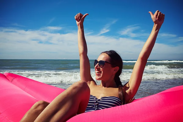 Eine Frau sitzt auf dem Luftgummifloß am Strand und hält — Stockfoto