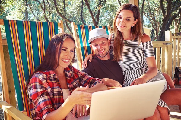 Eine fröhliche Gesellschaft von Menschen, die zusammen auf einen Laptop starren — Stockfoto