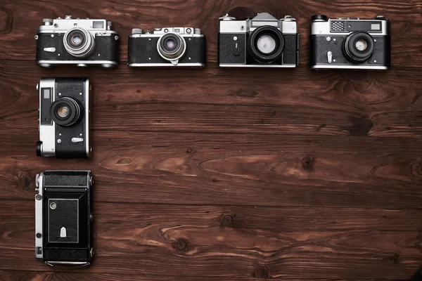 Vintage cameras lying vertical in the dark wooden flat area — Stock Photo, Image