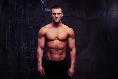 Karanlık duvara çıplak gövde ile poz atletik genç adam