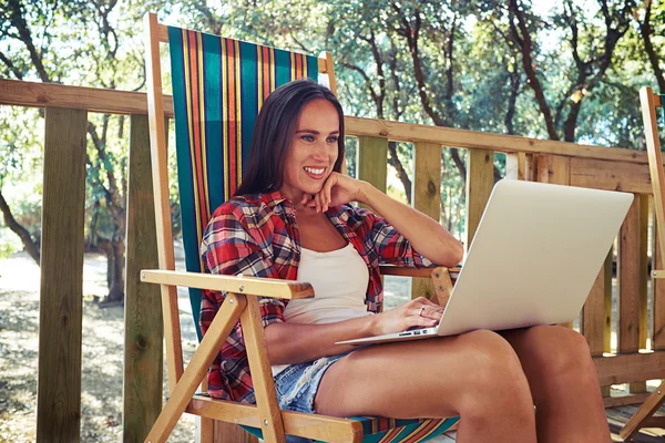 Toothy lachende vrouw is kijken naar het scherm van de laptop en — Stockfoto