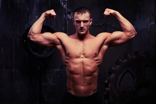 Junger Bodybuilder mit motiviertem Blick zeigt seinen gepumpten Bizeps — Stockfoto