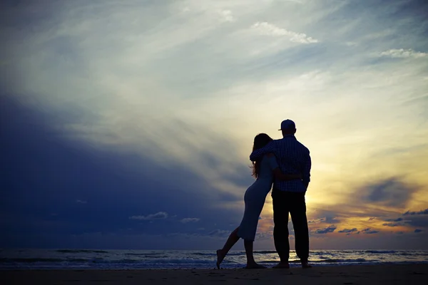 Silhouette eines Paares, das sich beim Blick auf den Sonnenuntergang umarmt — Stockfoto