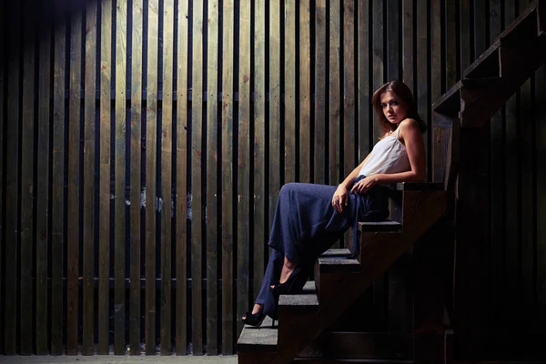 Erstaunliche junge stilvolle Frau sitzt auf der Treppe und schaut auf die Kamera — Stockfoto