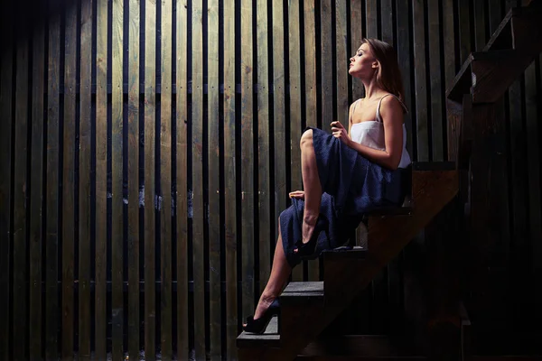 Mulher inspirada com pernas magras nuas posando em escadas de madeira em d — Fotografia de Stock