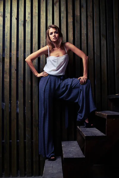 Modelo de moda moderna posando em larga posição em escadas de madeira, flo — Fotografia de Stock