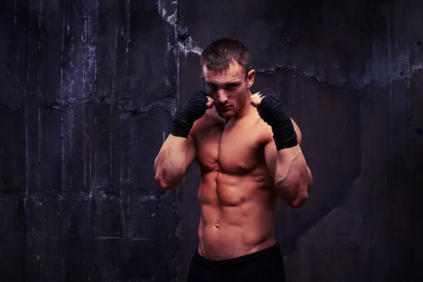 Piercing gaze of bare-chested man in sport shorts in studio agai — Stock Photo, Image