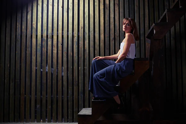 Weibliches Modell sitzt auf dem Rand der Holztreppe, — Stockfoto