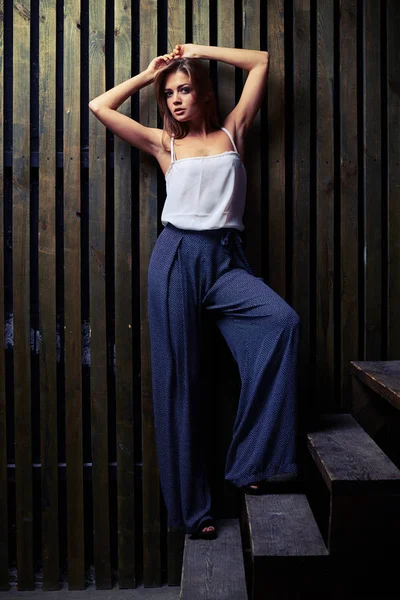 Pretty model with hands up leaning on the wall while posing at t — Stock Photo, Image