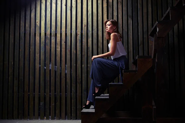 Entspannte junge Frau sitzt auf der Treppe, während sie nach unten schaut — Stockfoto