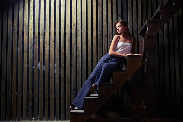Mujer joven en traje de moda está casi acostado en las escaleras con la mano —  Fotos de Stock
