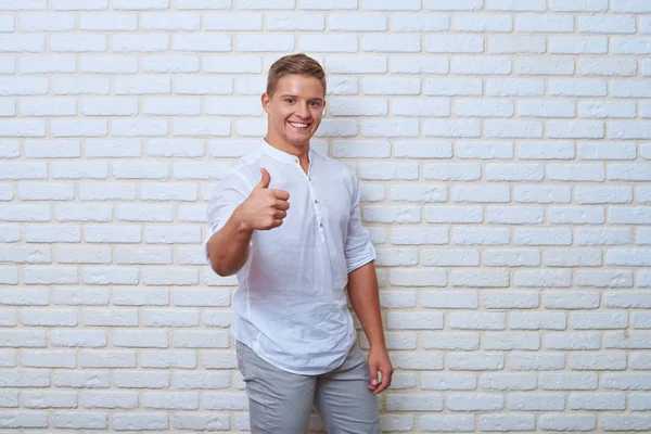 Confident young man giving ok sign while standing against white — Stock Photo, Image