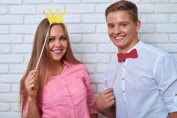Grappig zijn paar holding papier ' bow-tie en kroon, ze lachen — Stockfoto