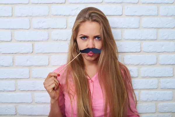 Drôle sourcils jeune femme attrayante tenant moustache en papier — Photo