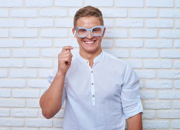 Uomo divertente in abiti casual in possesso di occhiali di carta durante la posa di un — Foto Stock