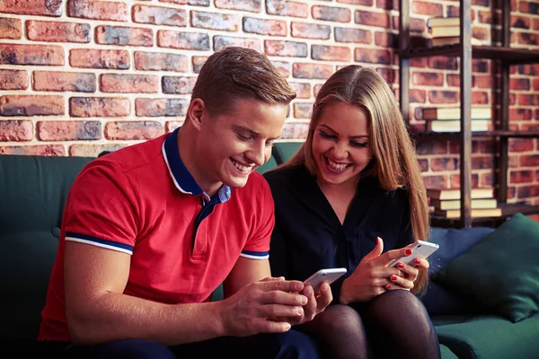 Smiley man och kvinna kopplar av på soffan och använder smartphones — Stockfoto