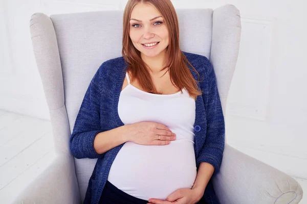 Nahaufnahme einer glücklichen Mutter, die ein Baby erwartet und im Sessel posiert — Stockfoto