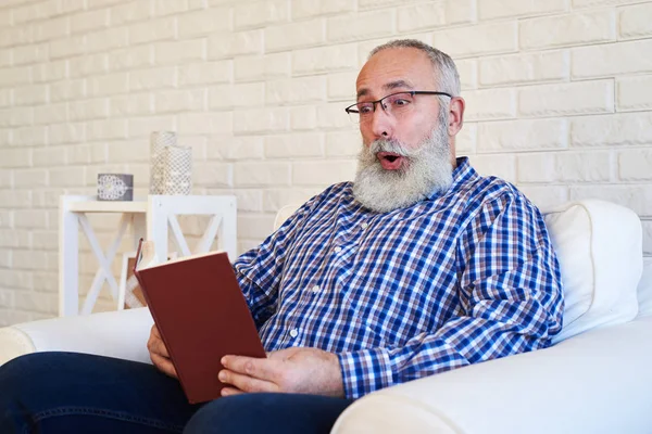 A beard elderly man reading a book