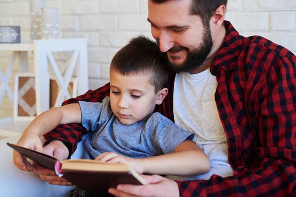 Vader en zoon lezen van een interessante boek samen in een armcha — Stockfoto