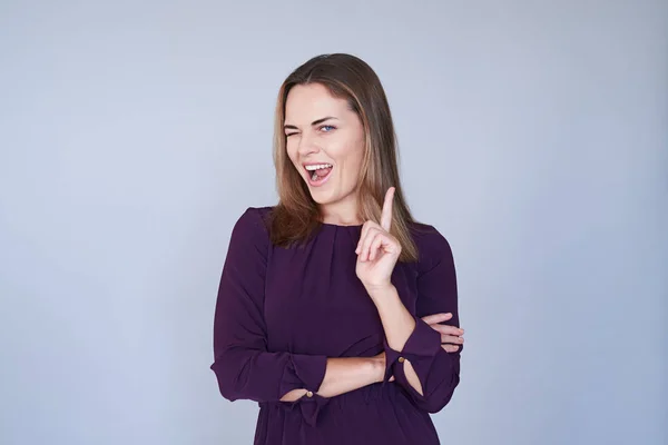 Glada kvinna blinkar när pekar ett pekfinger på kameran — Stockfoto