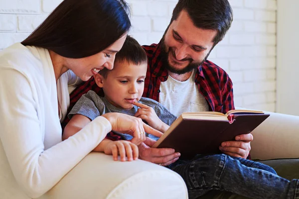 De beaux parents partagent un moment spécial avec l'enfant tout en lisant un in — Photo