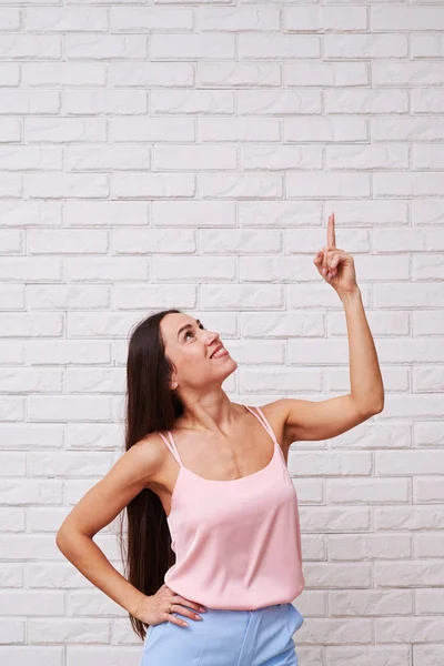 Mulher magro no topo rosado apontando o dedo para o espaço de cópia para cima — Fotografia de Stock