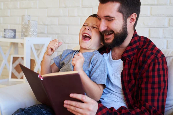 Son och pappa skrattar och läsa en bok — Stockfoto