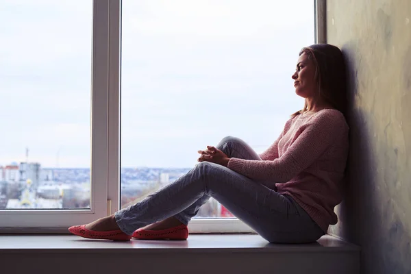 Menina cuidadosa com pernas longas sentado em um peitoril da janela e olhar — Fotografia de Stock