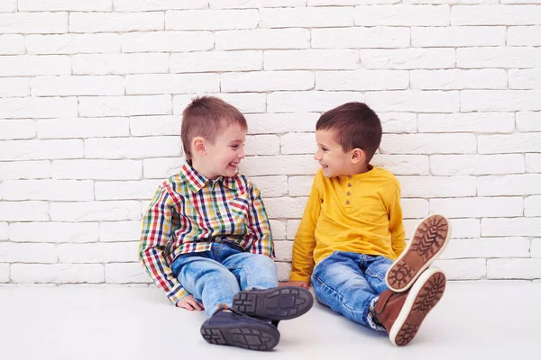 Heureux deux petits garçons assis sur le sol et se souriant — Photo