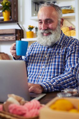Çay içme ve vakit ise dizüstü kullanarak memnun adam 