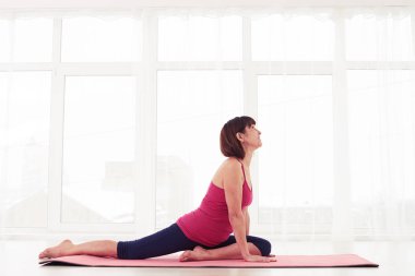 Olgun Bayan bir yoga öğesi bir mindere gerçekleştirme 