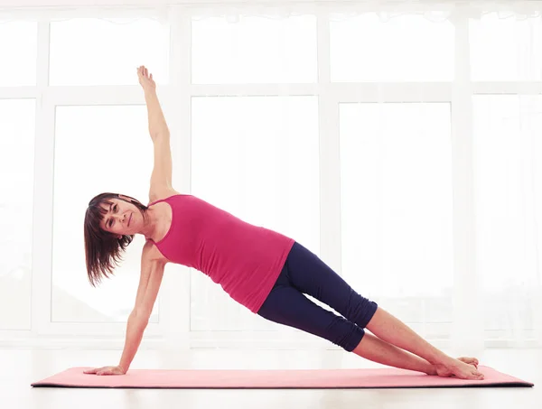 Une brune sportive pratique la pose de planche latérale de yoga dans la salle de gym — Photo